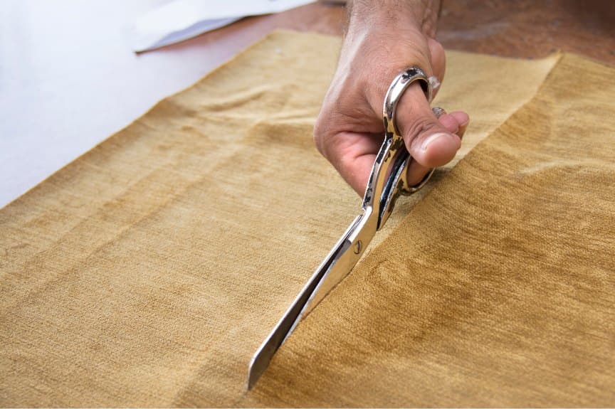 Hand cutting golden fabric with tailor's shears