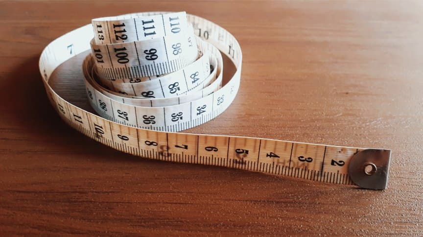 Tailor's measuring tape coiled on a wooden table