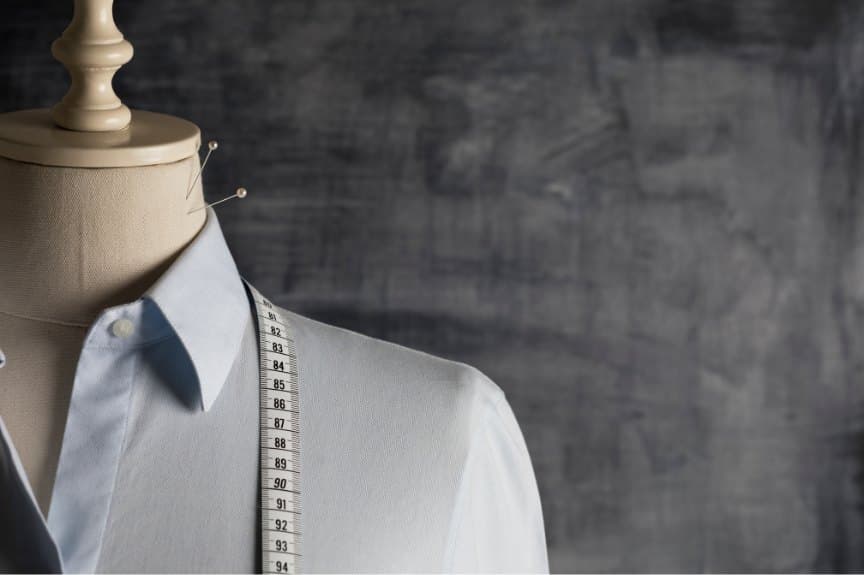 Pale-blue shirt pinned on a tailor's form with a measuring tape over the shoulder