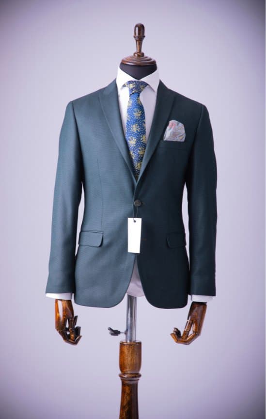 Elegant green ceremony jacket with a patterned tie and pocket square on a mannequin