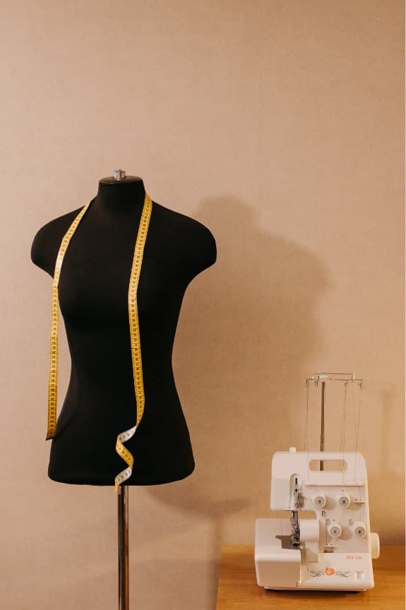 Black dress form with a yellow measuring tape in the fitting studio