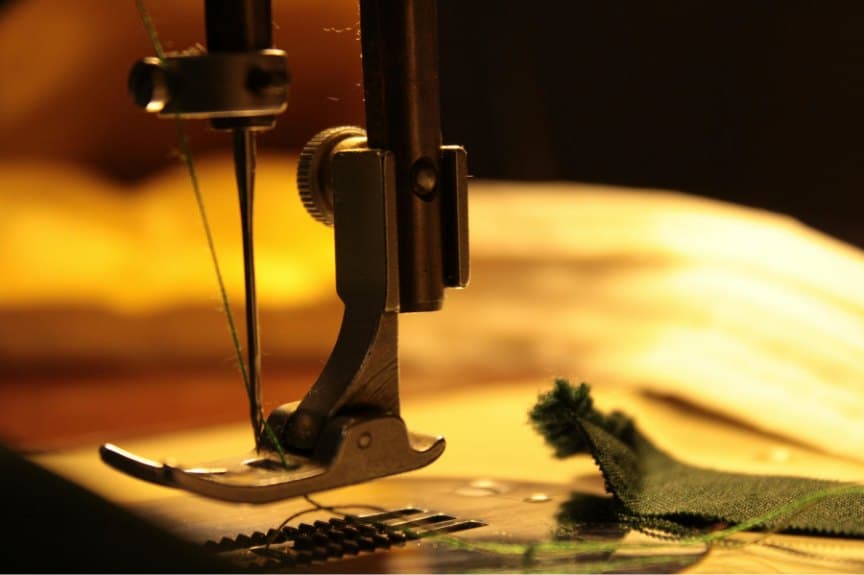 Close-up of a sewing machine needle at work in warm golden light