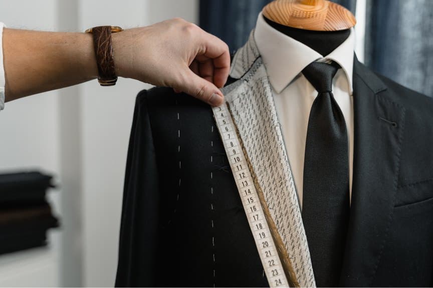 Tailor measuring a suit shoulder with a tape on a mannequin